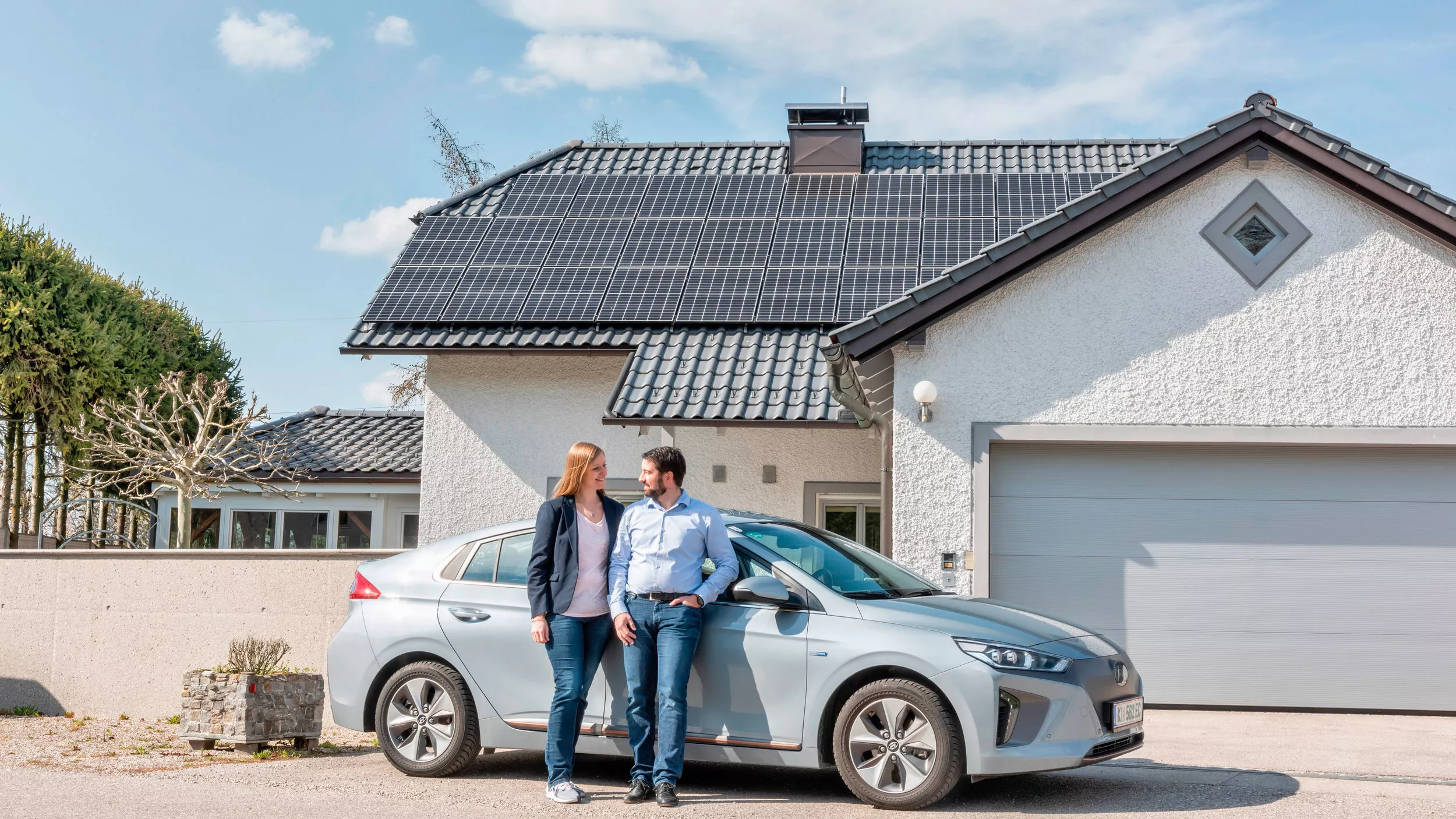 couple in front of car and house with modules